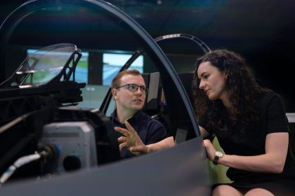Profissionais analisam o projeto de um cockpit de aeronave durante uma sessão de simulação.