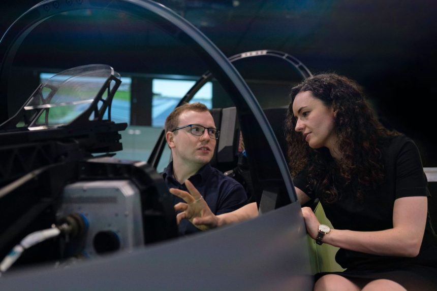 Profissionais analisam o projeto de um cockpit de aeronave durante uma sessão de simulação.