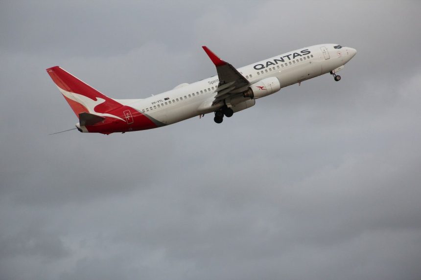 Avião Boeing 737-800 da Qantas decolando em meio a um céu nublado no Aeroporto de Melbourne.