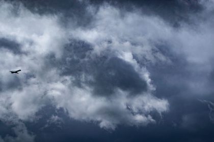 Avião solitário atravessando densas nuvens de tempestade em voo.