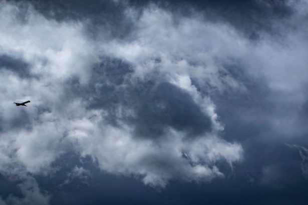 Avião solitário atravessando densas nuvens de tempestade em voo.