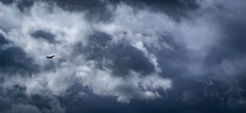 Avião solitário atravessando densas nuvens de tempestade em voo.